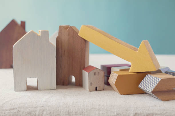 Wooden house models with a yellow downward arrow.